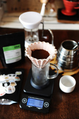 Ground coffee in pink ceramic origami dripper with paper filter. Alternative coffee brewing. Manual grinder. Gooseneck kettle. Electronic scale