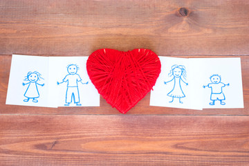 Red heart and happy family drawn on paper notes on the wooden background.
