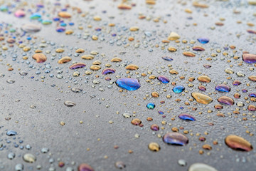 water droplets and oil products on the dark surface, colored spots on the surface of water droplets