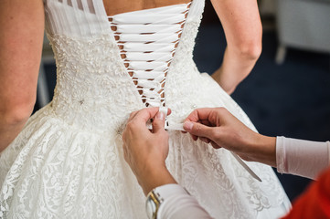 Back view of the wedding dress, mother's hands tie the bride's dress