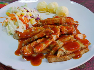 Close up of cooked and sliced chicken stakes served along with vegetable salad and mashed potatoes