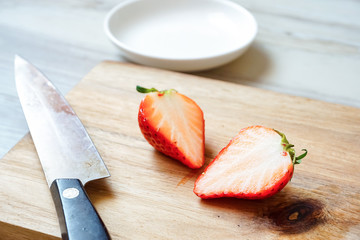 Strawberries cut in half on the cutting board.  まな板の上にある半分に切ったイチゴ