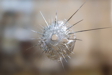 crack and split on the glass from a shot at it, the background is blurred brown