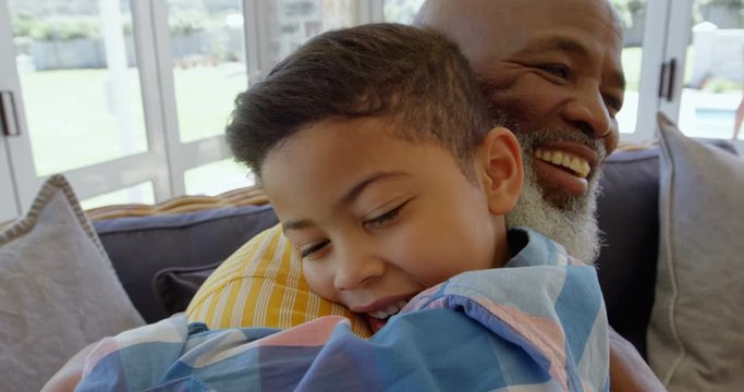 Side view of mature black father embracing his son in living room of comfortable home