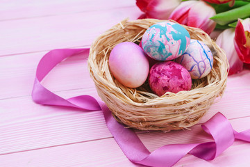 Beautiful Easter composition with decorated eggs and flowers on pastel wooden background
