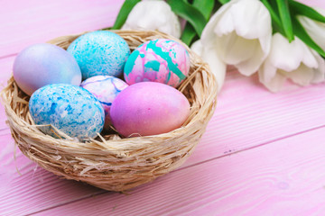 Easter background with colorful eggs and  tulips over pink wood. Top view with copy space