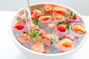 Strawberries soaked in water. Washing fresh fruit. on white.