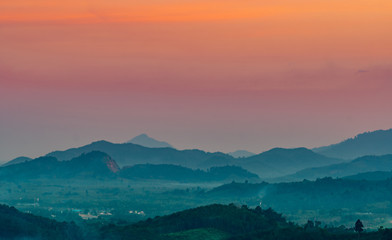 Beautiful nature landscape of mountain range with sunset sky and clouds. Rural village in mountain valley in Thailand. Scenery of mountain layer at dusk. Tropical forest. Natural background.
