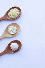 Garlic on wooden spoon on white background