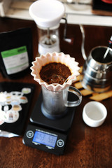 Blooming coffee in pink ceramic origami dripper with paper filter. Alternative coffee brewing. Manual grinder. Gooseneck kettle. Electronic scale