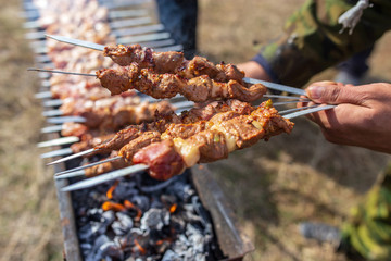 A man fries kebabs on skewers on the grill