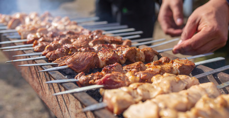 A man fries kebabs on skewers on the grill