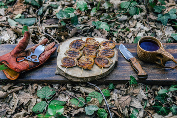 campfire red meat in pan, near the fire outdoors. bushcraft, adventure, tea, knife and camping concept.