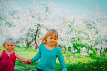 happy girls play run in spring nature, apple blossom