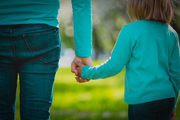 mother and little daughter holding hands in nature