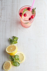 Refreshing summer drink with berry and lemon on a light wooden table. The concept of summer drinks with ice. glass with summer cocktail with straw.
