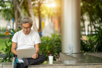 Fototapeta premium The elderly man used laptop in park