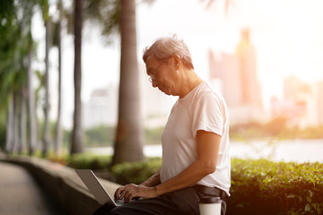 The elderly man used laptop in park