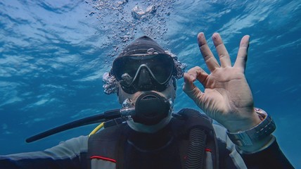 Man scuba diver underwater showing signal OK