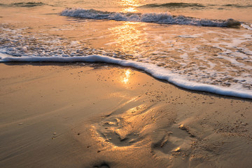 reflection of sunrise above the sea wave on the beach