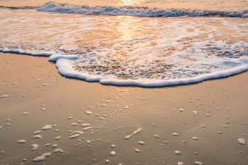 reflection of sunrise above the sea wave on the beach