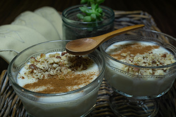 Rice pudding served in glass cups. Decorated. Close-up. Homemade dessert decorated with handmade napkins in a wicker tray.