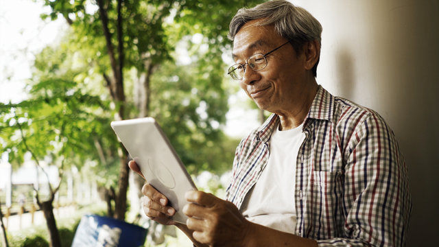 The elderly man enjoy to use tablet for relaxing