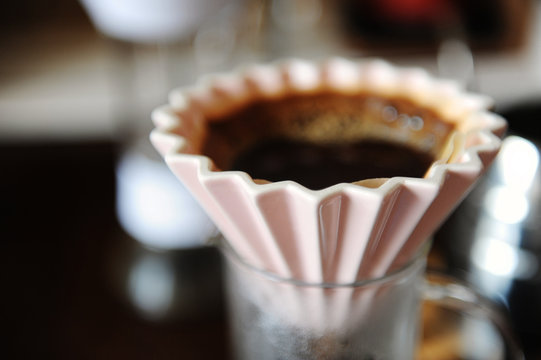 Alternative manual hand coffee brewing in pink ceramic origami dripper with paper filter. Close up