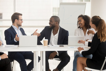 Multiracial employees sitting at boardroom desk listening team leader