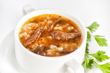 Bowl with delicious soup with meat and barley on white