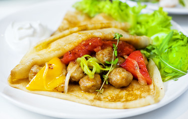 Thin delicious pancake with meat balls and pepper on white