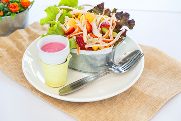 Close up fresh salad with boiled chicken and stawberry on bucket bowl on white background. on white background, black for copy space, view from top.