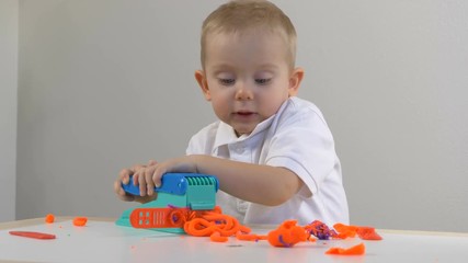 A two years old preschool child playing with modeling clay (compound). Smiling and looking at the camera. Early childhood education to children concept