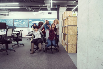 multiethnics business team racing on office chairs