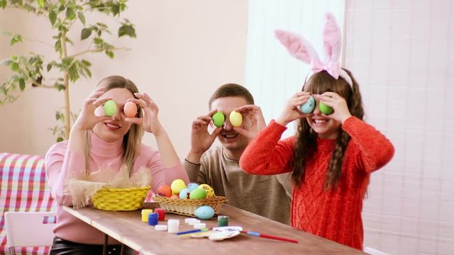 family, Caucasian appearance, smiling widely takes in the Easter egg and holding it at eye level fooling around.