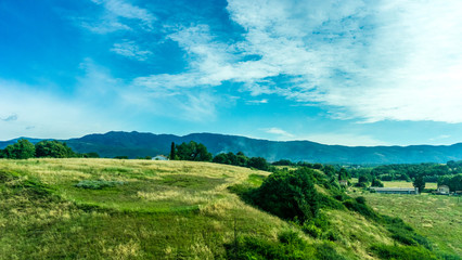 Obraz premium Italy, Rome to Florence train, a large green field with a mountain in the background