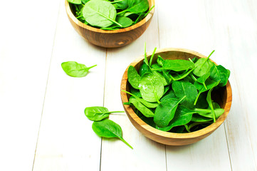 Fresh green spinach leaves on wooden bowl on white wooden rustic background Selective focus copy space. Baby young spinach leaves, Ingredient for salad, healthy food, diet. Nutrition concept.