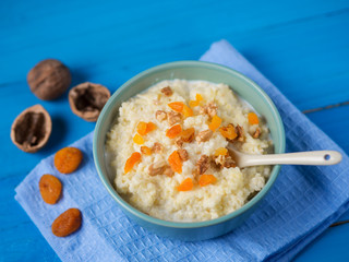 Millet porridge on a wooden blue table with nuts and dried fruits, dried apricots