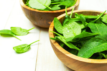 Fresh green spinach leaves on wooden bowl on white wooden rustic background Selective focus copy space. Baby young spinach leaves, Ingredient for salad, healthy food, diet. Nutrition concept.