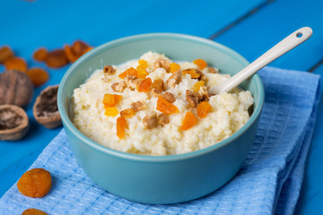 Millet porridge on a wooden blue table with nuts and dried fruits, dried apricots