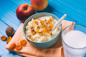 Millet milk porridge with Apple, walnut and dried apricots on a wooden blue background