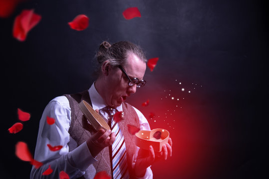 Crazy happy guy holding red heart gift box - present valentines day - love - with flying petals - roses