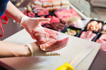 Woman in butcher shop selling meat fillet