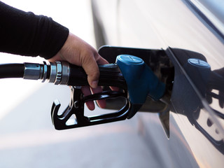 Closeup hand man pumping gasoline fuel in car at gas station.