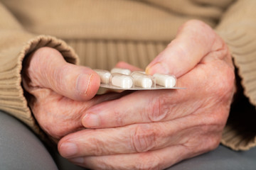 Elderly hands holding pills