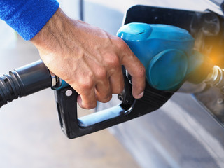 Closeup hand man pumping gasoline fuel in car at gas station.