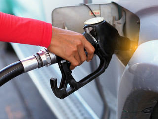 Closeup hand man pumping gasoline fuel in car at gas station.