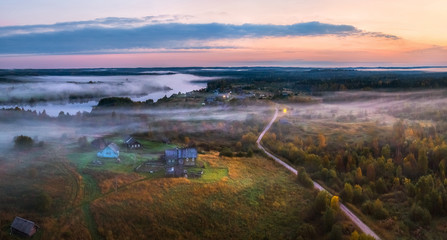 Foggy panorama of the village on the lake. Autumn dawn. Fog over the village, houses, village. On the shore of the lake in the fog.