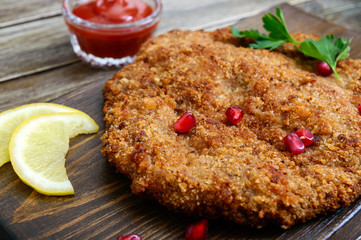 Large Viennese schnitzel on a wooden background. Meat dish. Close up