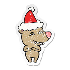 distressed sticker cartoon of a bear showing teeth wearing santa hat